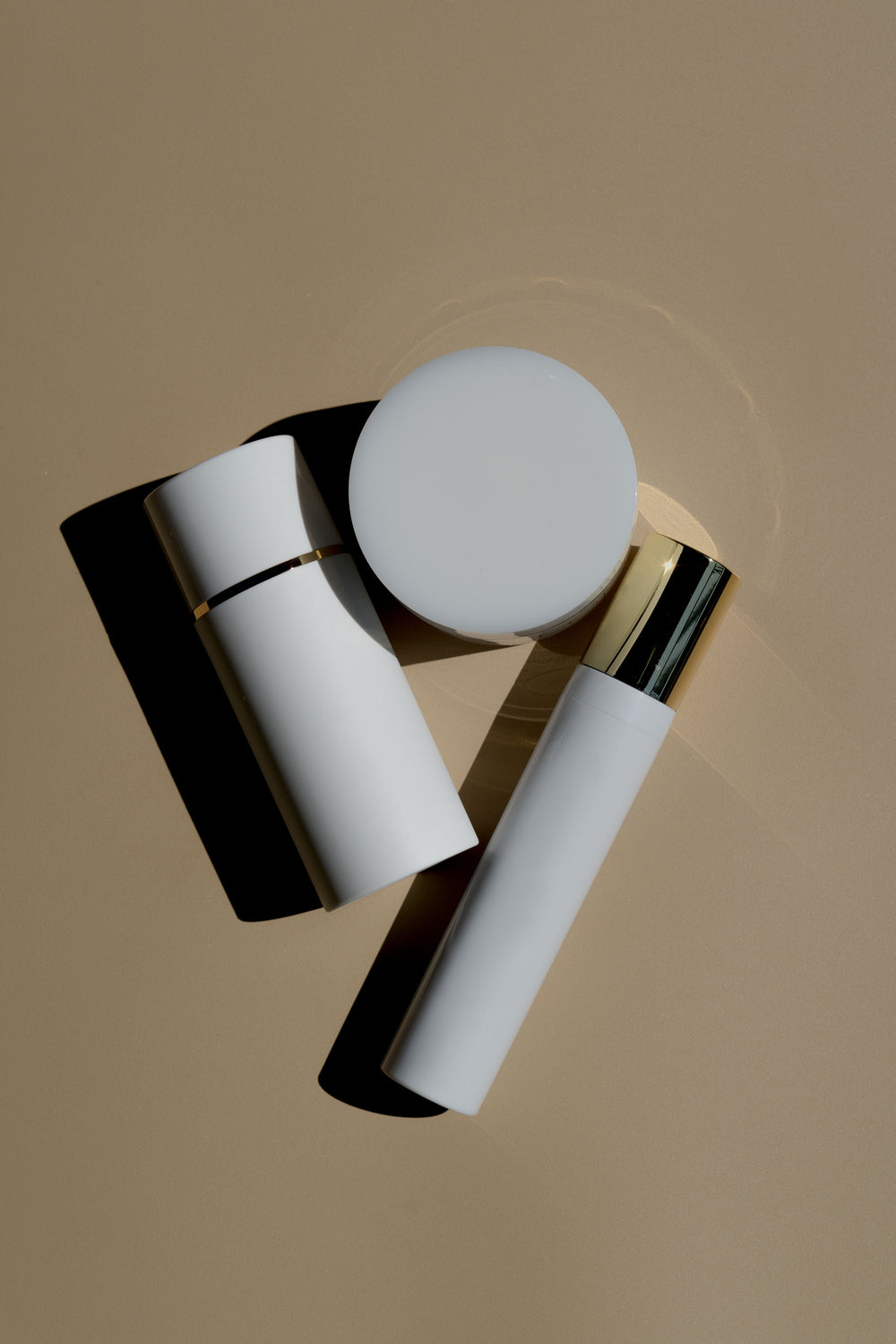 Minimal skincare tubes and jar arranged on a soft beige background