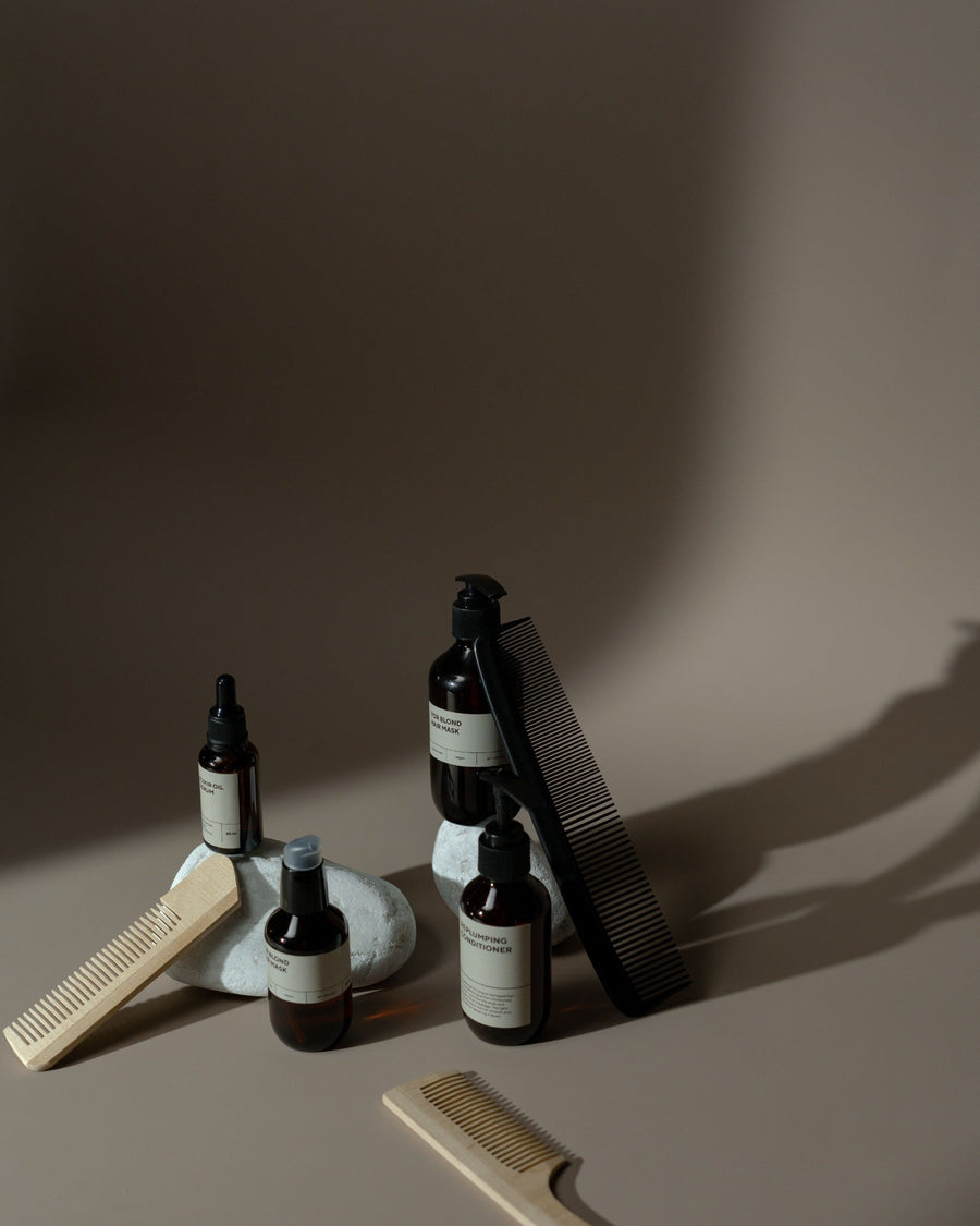 Hair care bottles and combs arranged on a warm neutral background